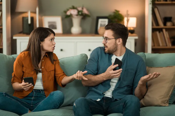 couple sitting on a couch and resenting each other.