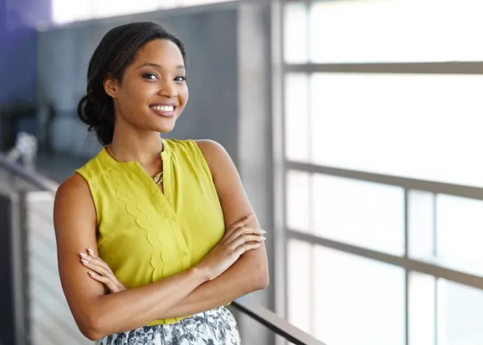 Friendly african american woman standing with arms crossed in a modern bright office