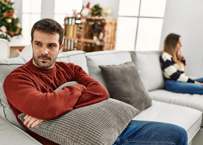 Young hispanic couple with problems sitting on the sofa in silence at home.